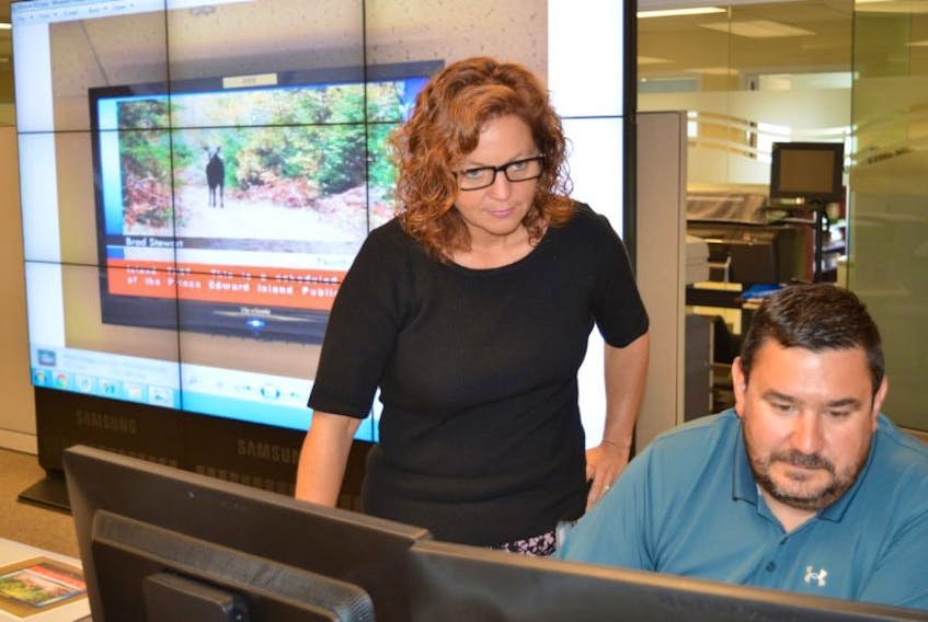 Tanya Mullally, provincial emergency management co-ordinator with P.E.I.’s Emergency Measures Organization (EMO), and Jason Thistle, public safety officer, work in EMO’s command centre in Charlottetown on Thursday. Behind them is a TV screen that demonstrates what an alert to the public would look like on a TV screen. A message in red ticker would display across the bottom.