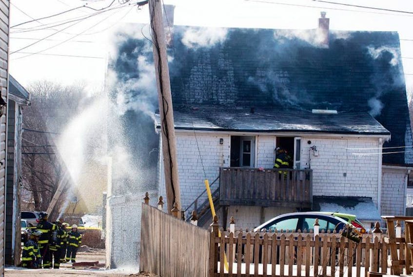 Charlottetown fire fighters hose down the side and back of a house on University Avenue Saturday during a fire that left five people homeless.