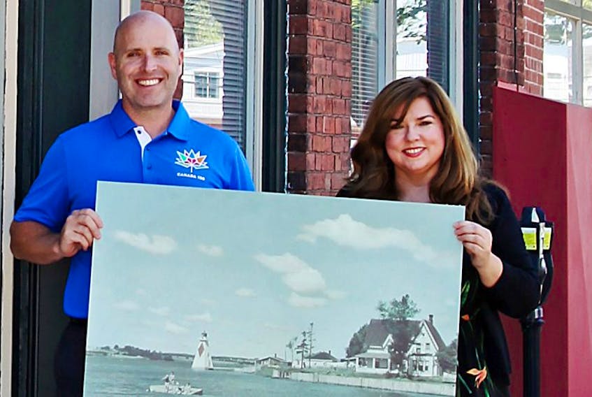 Coun. Greg Rivard, chairman of the planning and heritage committee, and Natalie Munn, heritage researcher and collections co-ordinator, hold a photo of a group swimming off Victoria Park and Queen Elizabeth Drive in the 1950s — just one of the images included in the city’s latest exhibit, “Picturing A City: Summertime”.