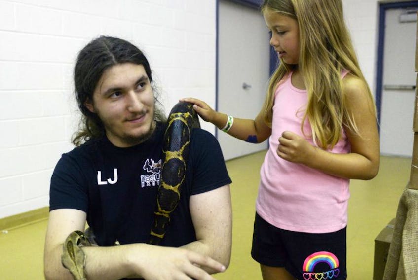 Seven-year-old Ashlyn Gaudet, of Summerside, checks out a Boa Constrictor being held by Leonel Evangelho, of East Coast Exotics in Kingsboro, during the second annual P.E.I. Reptiles and Exotics Expo held in Stratford recently. From snakes and lizards to rats and hedgehogs, the event hosted some of the Maritimes top breeders.