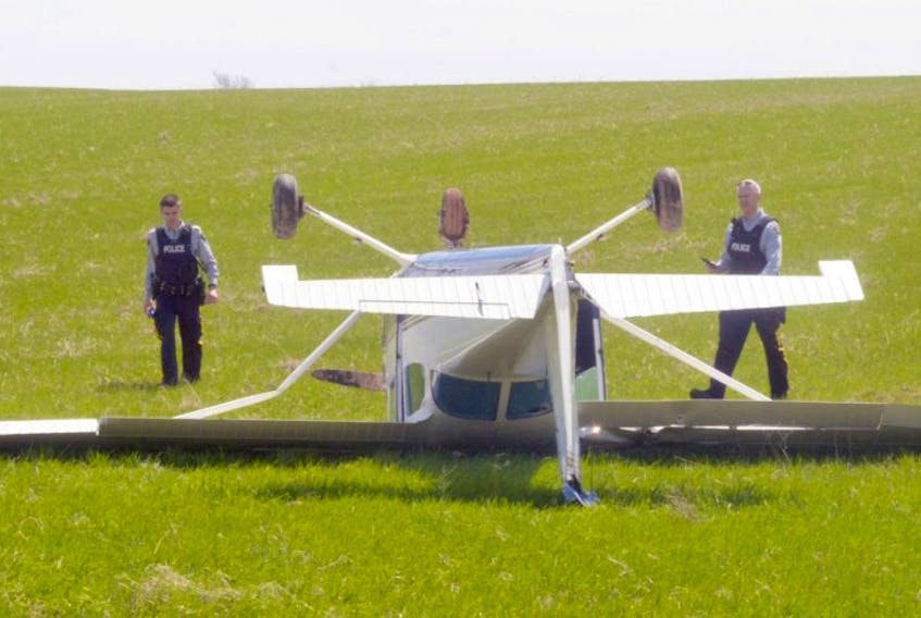 RCMP officers look over the scene of a plane that crash-landed in Hampton due to engine failure on Sunday afternoon. Police said the pilot reported the plane was flying at about 2,000 feet altitude when the engine began to fail.