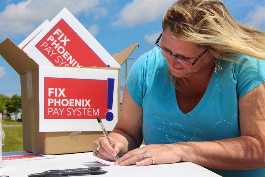 Heather Ford, spokesperson for PSAC P.E.I. chapter, signs a postcard that will be sent to MP Scott Brison asking for the Phoenix pay system to be fixed.