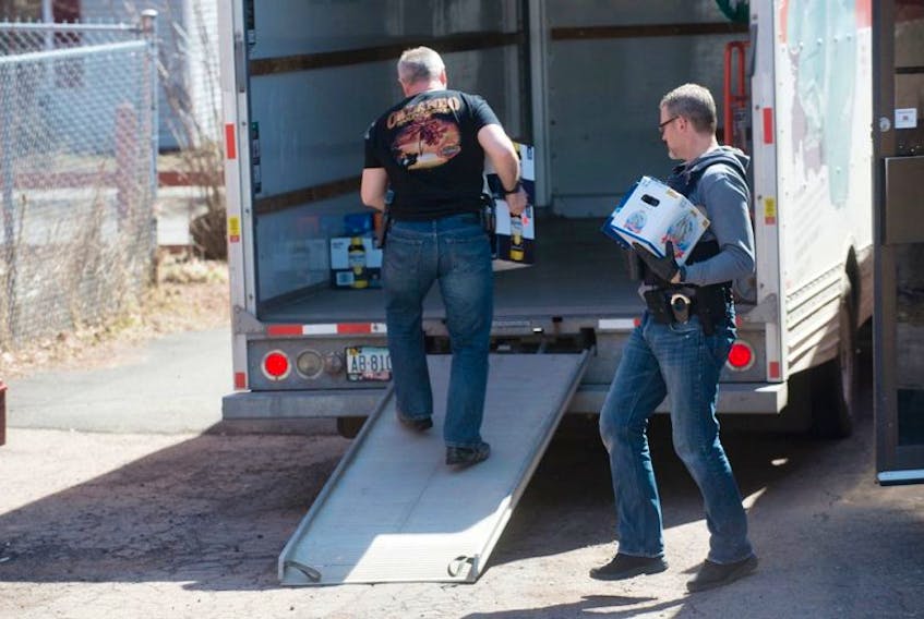 Police carry cases of beer they seized when they executed a search warrant on a Hells Angels hangaround club at 205 Fitzroy St. Saturday morning. Police also seized items from the Charlottetown Harley Club on University Avenue.