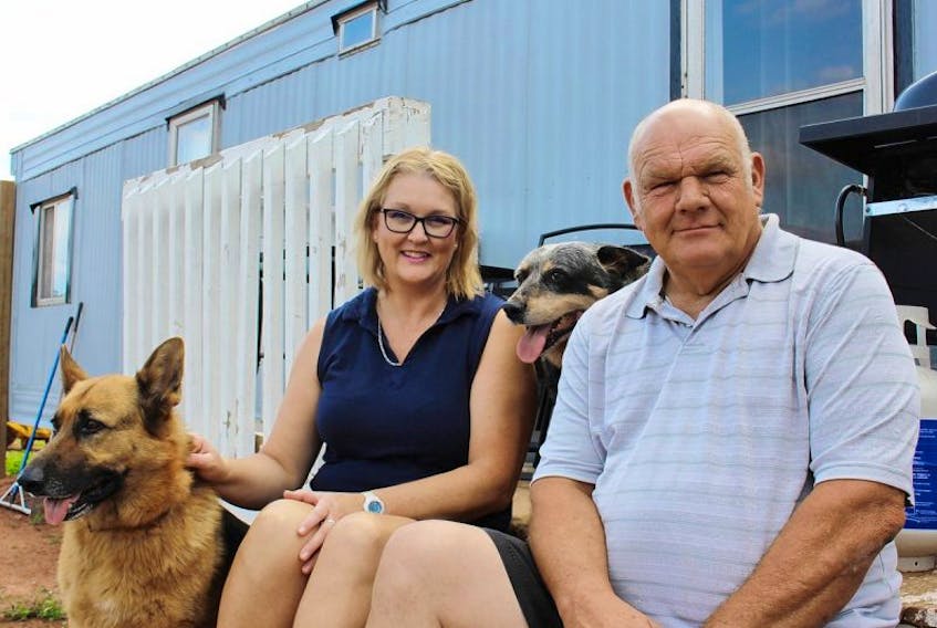 Kathy Pendergast, left, and Donnie Arsenault, with dogs Luck and Jack, lost their home in a fire in May. Now they are now in a battle with their insurer over the value of the property.