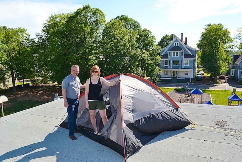 Prince Street Elementary School principal Erin Johnston and Philip Brown of the Prince Street Home and School prepare Johnston’s tent atop the school’s roof Wednesday. The school’s students raised more than $7,000 through sponsorships for a community cleanup, meeting their goal to have their principal camp out for a night on the roof.