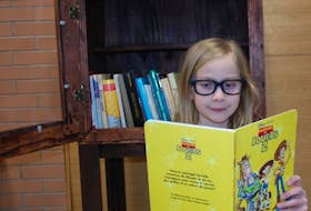 Arielle Foulkes, 8, a French first language student at École Francois-Buote, reads a book from the Little Free Library in the Royalty Centre in Charlottetown.