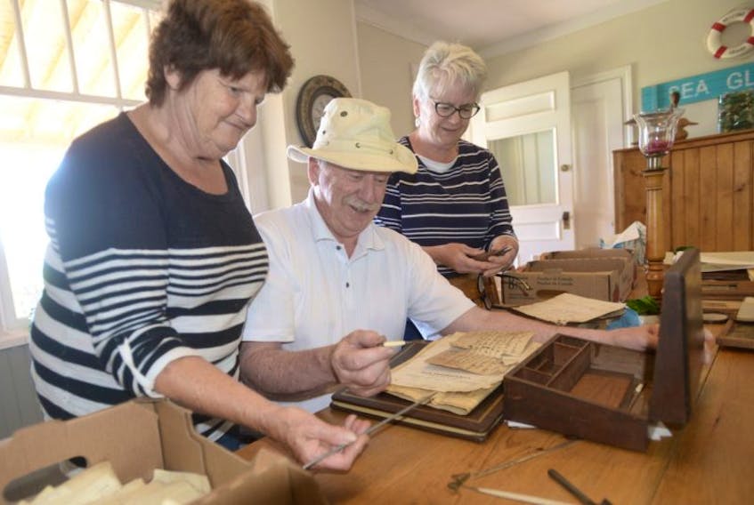 Estelle and George Dalton, from left, look over some items found in their home that date back to the 1870s with Brenda Boudreau, of the Victoria Historical Society. The couple have found receipts, early rug hook tools, as well as wool clothing in a home they purchased last year.