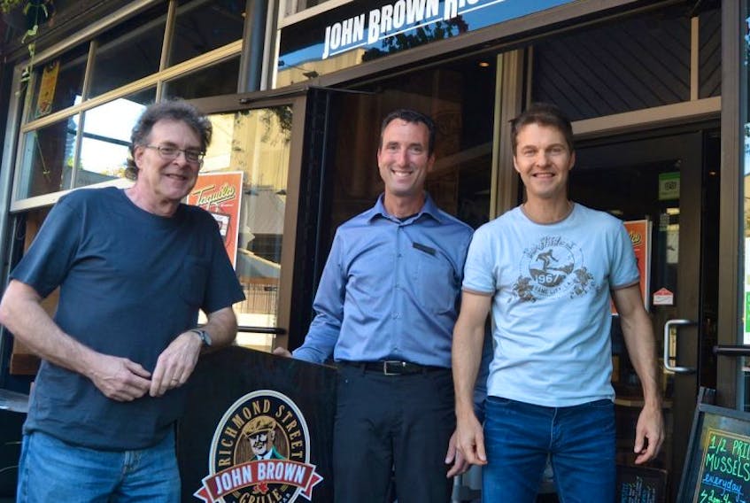 Taquila’s bass player Russell Kerr, left, and lead vocalist Jeff Morris, right, confirm details for this weekend’s band reunion at the John Brown Richmond Street Grill with manager Jeff Sinnott. The popular 1980’s Canadian rock band is reuniting for two shows, tonight and tomorrow.
