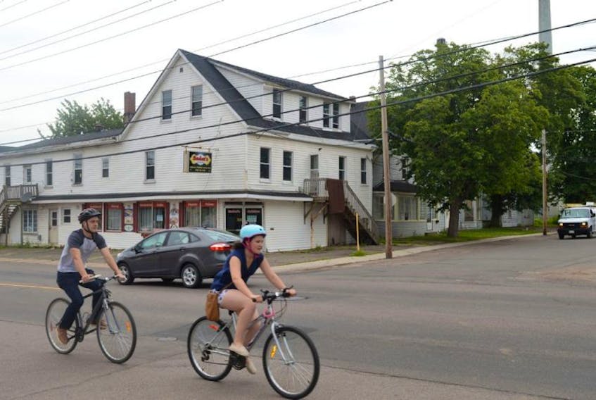 Two cyclists ride by some of the properties set for demolition in August. Holland College is making preparation to build a new 80-bed student residence that will cost nearly $7 million.
