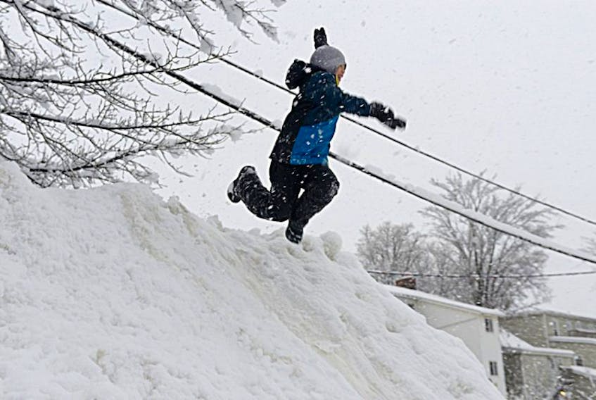 Willy Bripanisakorn, 8, makes a leap from a high snow pile cleared from a parking lot behind his home Wednesday. All schools in the province were cancelled for the day. Environment Canada is warning that tomorrow is likely to bring a repeat of todayâs weather.