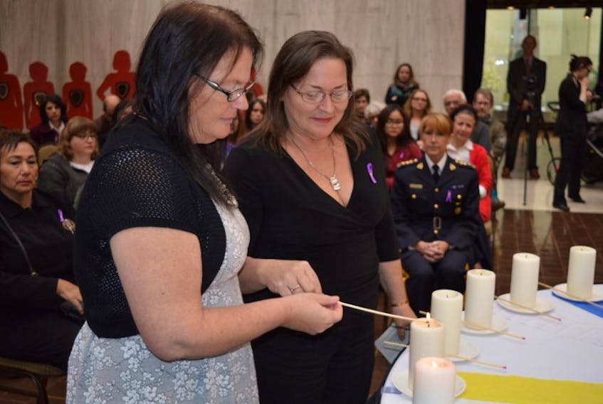 Lisa Cooper, left, president and chief of the Native Council of P.E.I., and Nancy MacLean, also with the Native Council of P.E.I., light a candle in memory of the 14 women murdered at lâEcole Polytechnique de Montreal and the 10 women murdered in P.E.I. since 1989.