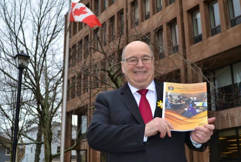 Finance Minister Allen Roach holds a copy of the 2017 provincial budget in front of the government buildings on Friday. 