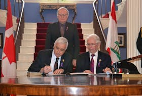 Premier Wade MacLauchlan and Lieutenant Governor Frank Lewis look on as Pat Murphy signs an oath of office as Prince Edward Island Minister of Rural and Regional Development.