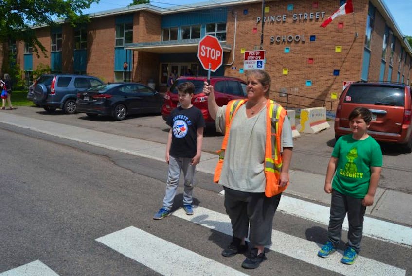 Crossing guard Dana Doyle assists Grade 4 students Matthew Stanley, left, and Connor MacEwen on a busy Charlottetown street. 
