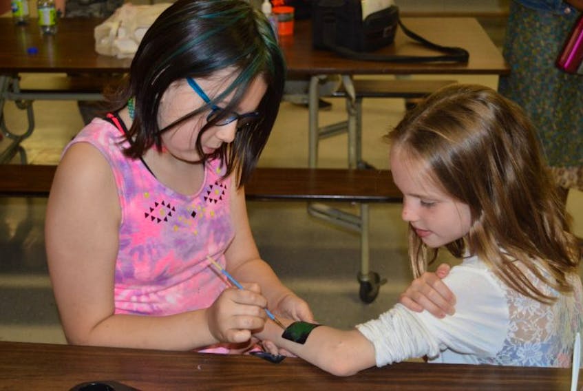 Madelyn Affleck, left, paints a turtle tattoo on the arm of Brooklyn Pirch at Mount Stewart Consolidated School on Friday. The school and Mi’kmaq Confederacy of P.E.I. were marking the National Day of Healing and Reconciliation. Pirch was also sporting a tattoo on her cheek of an eagle. The turtle and eagle are two of the seven sacred Mi’kmaq teachings.