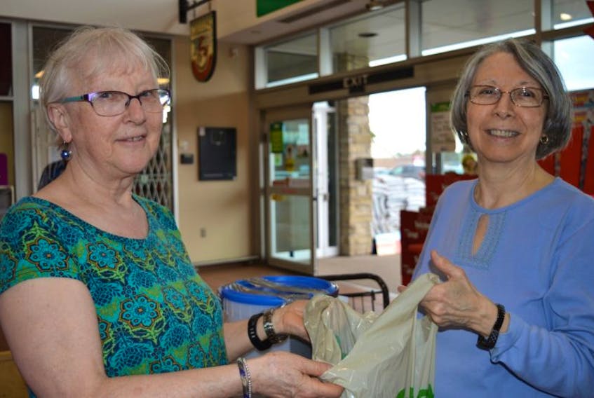 Dolores Gaudin of Charlottetown donates some fruit snack packs and women’s hygiene products to volunteer Gail Metcalfe at Sobeys Friday as part of the second annual Care Fair. 
