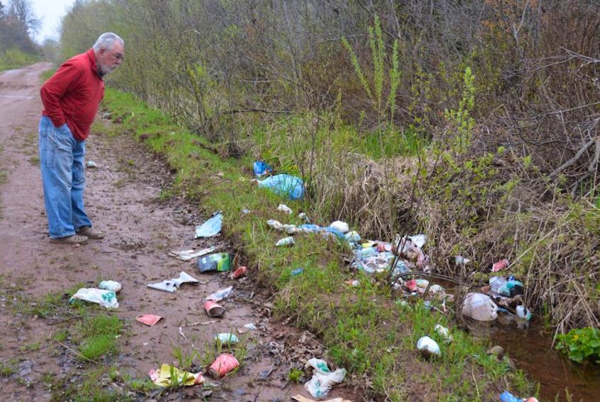 Arthur Davies looks over a mess of trash left on the side of the road near his farm on the Emery Road in Linkletter. 
