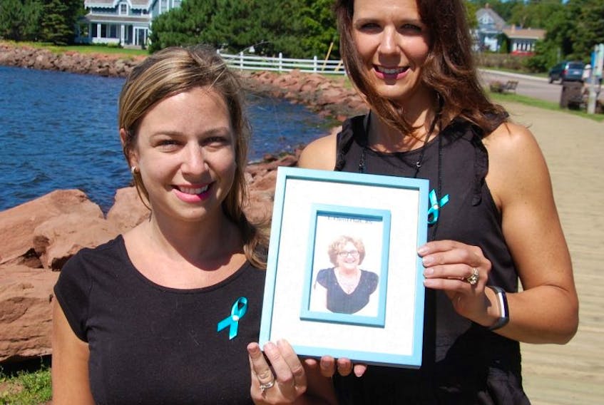 Jillian Forbes, left, and her sister Jennifer Bowness hold a photo of their late mother Cheryl Clark, who died of ovarian cancer in March. The sisters are organizing the first annual Ovarian Cancer Walk of Hope in Charlottetown in memory of mom.
