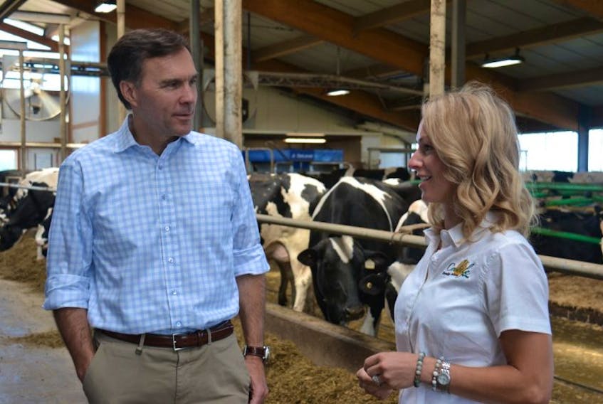 Federal Finance Minister Bill Morneau, left, talks to Amber Craswell of Crasdale Farms during a tour of a dairy barn in South Rustico on Wednesday.