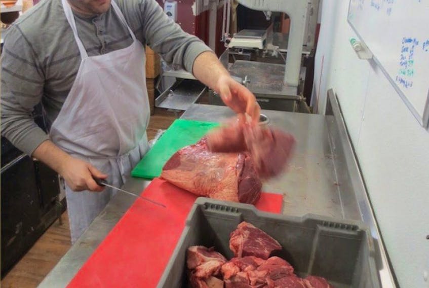Michael Frizzell, owner of Mike’s Queen Street Meat Market, starts butchering a beef hip to grind into burgers for Burger Love. The month-long event starts Friday, March 31. 