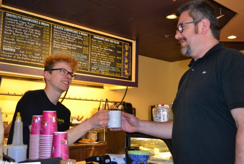Beanz staff member Duncan Brooks, left, serves up a cup of coffee to the Charlottetown shop’s new co-owner, Kaan Ulkan on Monday.