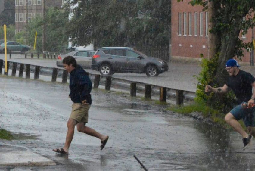 Two men head for cover on Prince Street in Charlottetown as a sudden downpour hits the city on Wednesday. Environment Canada had at one point issued a severe thunderstorm warning for all of Prince Edward Island. 