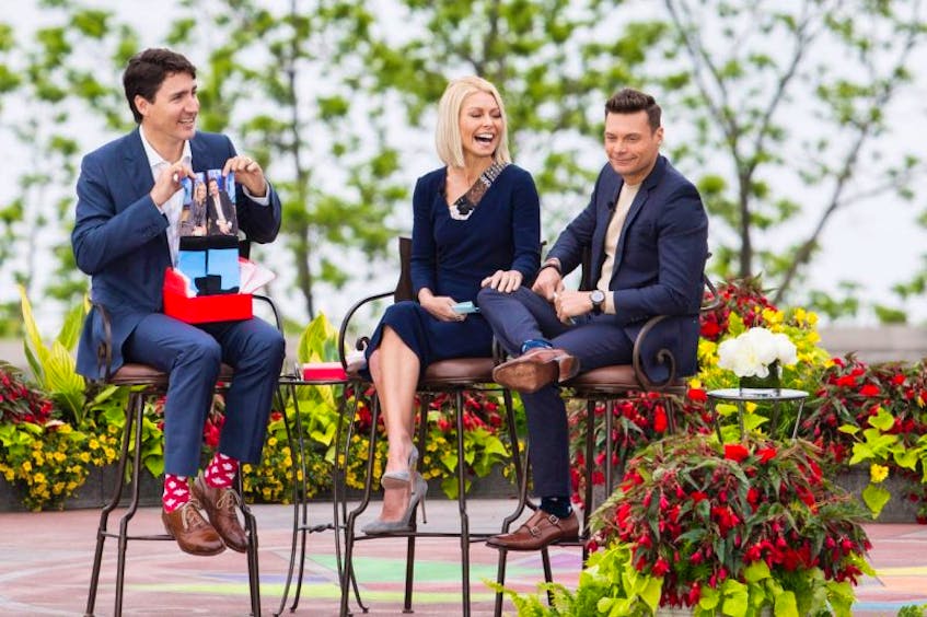 Prime Minister Justin Trudeau, left, holds up a pair of socks that he received as a gift from Kelly Ripa, centre, and Ryan Seacrest during his appearance on Live with Kelly and Ryan in Niagara Falls, Ontario on Monday, June 5, 2017. 
