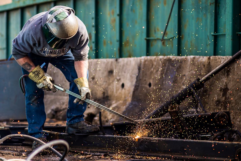 A worker at BMI Ltd. in Oakhill uses a torch to cut scrap metal to market size.