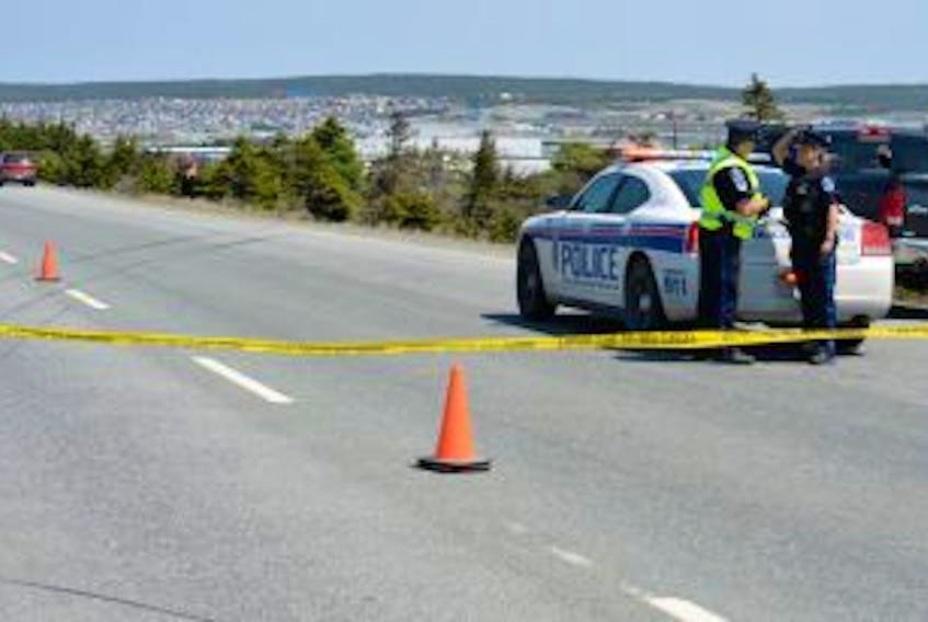 ["<br />Royal Newfoundland Constabulary officers Sgt. Jim Smith, left, and Const. Stephanie Carter, right, converse with one another at the scene of Sunday's serious single motor vehicle accident on the Outer Ring Road which occurred just before 11:30 a.m. The lone occupant of the vehicle – a male driver – lost control of his car and went over an embankment landing in a dense area of trees, as seen in the background. Police had the eastbound lane from the Manuel's Overpass Bridge to Donovan's Industrial Park closed to vehicle and pedestrian traffic while they conducted their investigation and removed the vehicle from the wooded area. At far left is RNC forensics identification section officer Const. Pat Hickey, photographing the accident scene as part of the investigation. The skid marks are where the vehicle operator lost control of his car and went off the road."]
