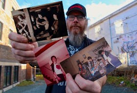 Geoff Younghusband, a longtime friend of John Fisher, holds pictures of Fisher from throughout his life. The band in the photo on the left is Potmaster, which featured (from left to right) Younghusband, Tony Tucker, Fisher and Natalie Noseworthy. The band on the right is Tough Justice and featured (left to right) Dean and Rod Locke, Llewellyn Thomas and Fisher. — Andrew Waterman/The Telegram
