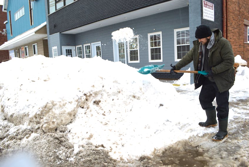 Nathan Quinn of Alder Point clears the sidewalk in front of J. Francis Investments on George Street, Sydney, Friday. A record 179.8 cm of snow was registered at the Sydney airport in January, the most since records have been kept dating back to 1870. Sharon Montgomery-Dupe/Cape Breton Post