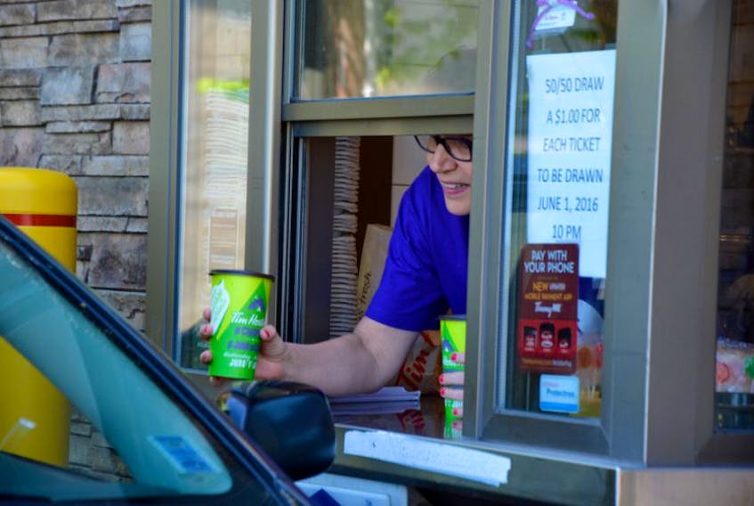 <p>Sherri Reynolds, an employee at Scotiabank Windsor, helps out at the drive-thru for Camp Day at Tim Hortons in Windsor.</p>