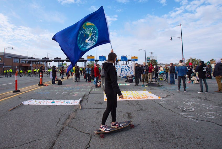 Rose Starr skateboards with an Earth flag at the Macdonald bridge climate protest Monday, Oct. 7, 2019. - Tim Krochak