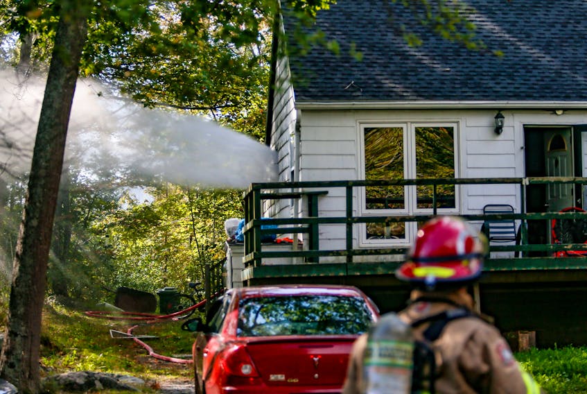 A blast of water and air comes out of a window of a home at 961 Cobequid Rd., near Lakeview, N.S., on Monday, Oct. 1, 2018. One woman was taken to hospital after being checked by paramedics. The blast of water and air is a process called hydration ventilation that helps to expel heat and smoke when fighting a fire. (TIM KROCHAK / The Chronicle Herald)