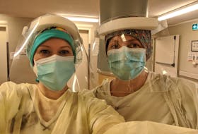 Megan Kean, left, and April Stevens suit up in personal protective equipment as they ready themselves for work amid the ongoing COVID-19 pandemic. CONTRIBUTED