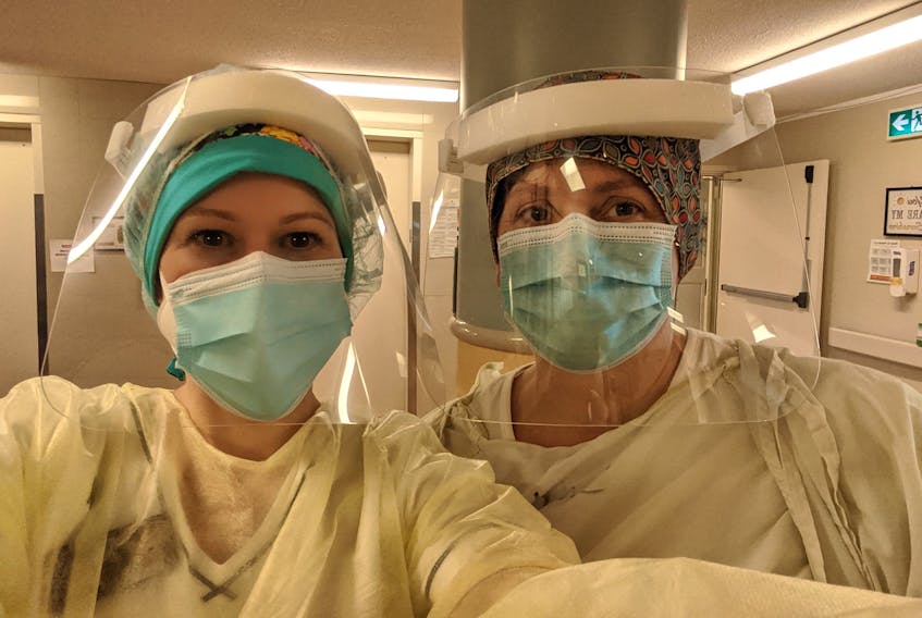 Megan Kean, left, and April Stevens suit up in personal protective equipment as they ready themselves for work amid the ongoing COVID-19 pandemic. CONTRIBUTED