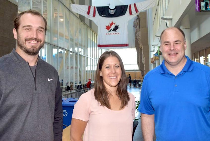 Officials from Hockey Canada were in Truro this week to tour the Rath Eastlink Community Centre and surrounding area in advance of the world junior A hockey championship tournament to be played at the facility in December. Seen standing underneath a giant-sized Hockey Canada jersey on display at the RECC, are from left, Hockey Canada officials Dave Hysen and Corinne Ethier, and Dave Ritcey, chairman of the host committee.