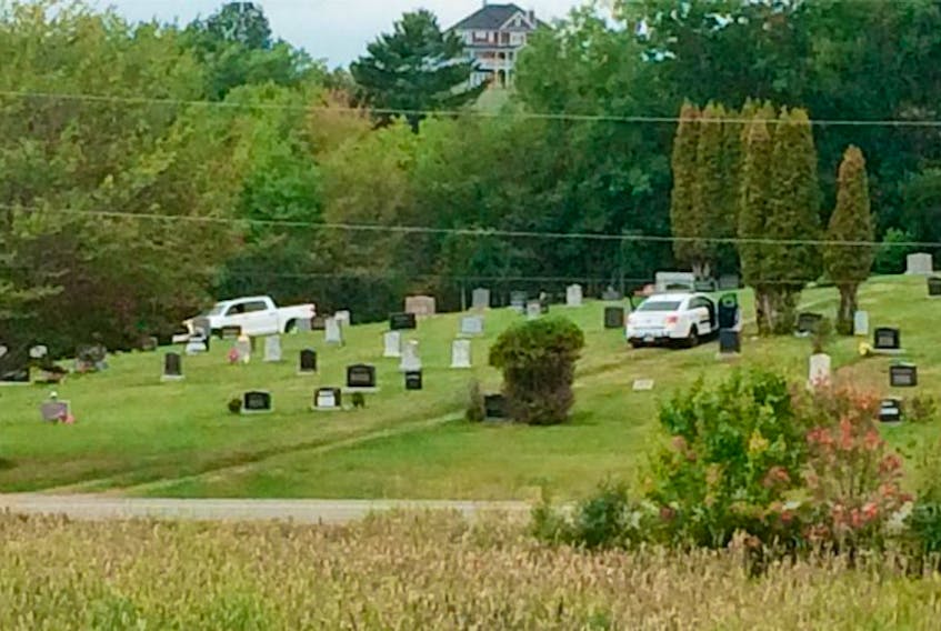 The truck belonging to the man who was shot by police Sunday night, along with a police cruiser, sit at the Lockerbie Memorial Cemetery.