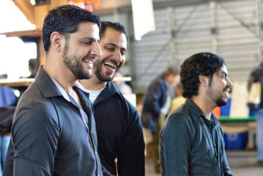 Ahmad Alhraki, from left, Alla Alhraki and Rafaat Harb serve customers at the Halifax Seaport Farmers’ Market on Saturday.