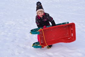Four-year-old Julie Reid picks up her sled, ready to climb the hill by Ecole Acadienne de Truro for another slide. 