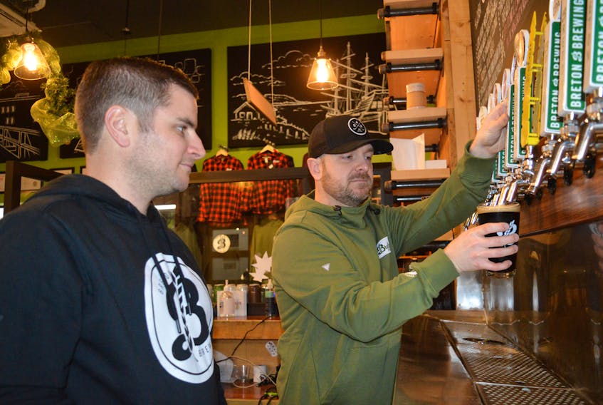 Breton Brewing Co. co-owner Andrew Morrow pours a glass of beer while his business partner Bryan MacDonald looks on in the taproom earlier this week. Following a year of adversity caused by the global COVID-19 pandemic, the beer business is seeing improvement through the Christmas season. CHRIS SHANNON • CAPE BRETON POST