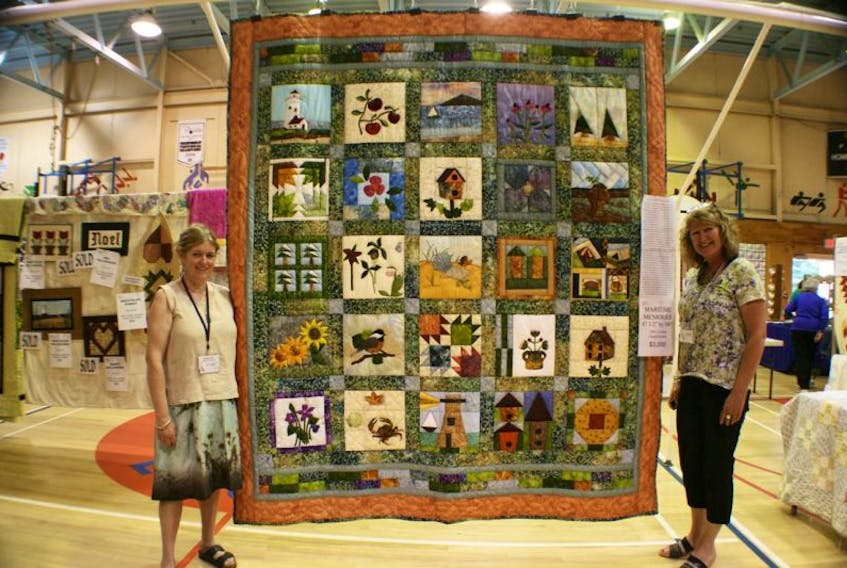Pedvac executive director Val MacDermid, at left, and executive assistant Anne Goodwin, right, are all smiles as they display the 'Maritime Memories' quilt at the Lupin Quilt and Craft Fair in Port Elgin on Sunday. The ladies have a lot to smile about as the quilt, which was created as a fund-raiser for Pedvac, was sold for $3000 during the annual quilt fair on the weekend. Proceeds from the sale of the quilt will help support Pedvac's many community based programs and services.  LEBLANC PHOTO