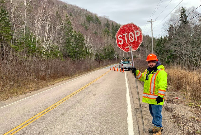 Ryan Tobin, an employee at Direct Traffic Control, holds a stop sign on Highway 216 near Eskasoni this week. Crews were installing fibre-optic cables along the route, limiting travel to one lane in some sections. Chris Connors • Cape Breton Post