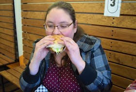 Joan Keller bites in the "flavour town" burger at Hub Grub during Truro Burger Week. The initiative exceeded past years' records, raising $10,746 with over 5,263 signature burgers sold and $220 additional donations at nine local establishments.