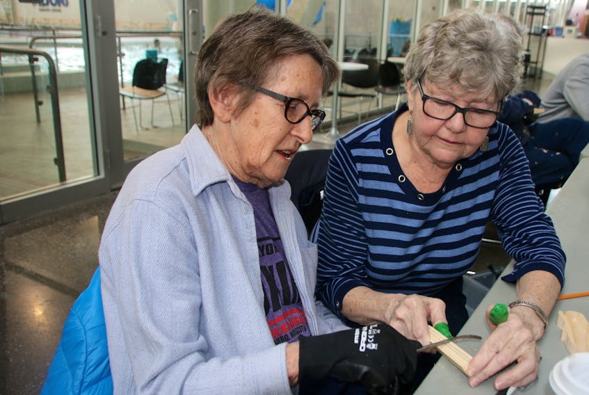 Judy Decker, left, got some help from Cathy Olsen when she tried woodcarving for the first time. Decker, who has Parkinson’s disease, hopes carving will help her with dexterity. LYNN CURWIN/TRURO NEWS