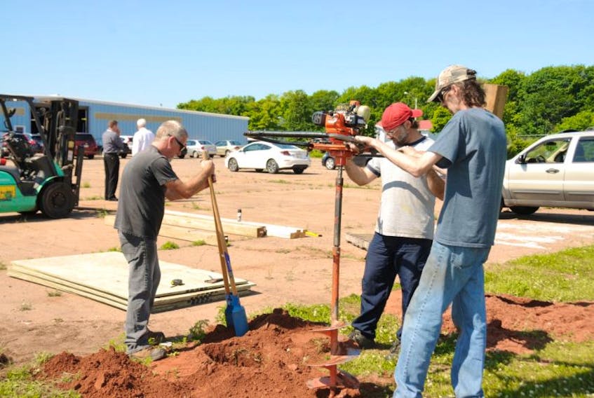 <p>Tube-Fab employees Bill Hearn, left, Andy Simmons, centre, and Kevin Kieren work to install posts that will hold the company’s new graffiti wall. Tube-Fab is installing the wall to encourage artists to use it instead of illegally painting on the buildings and signage in the Summerside Industrial Park.&nbsp;</p>