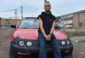 Jesse Crockett sits on the hood of his 1996 Acura Integra sedan, the only car he and his best friend Will MacLeod got to work on together.