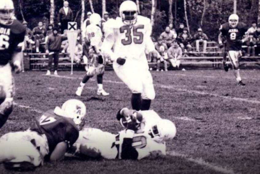 UCCB Capers player George Nimako, centre, is tackled by an Acadia Axemen player as teammate Phillip MacKenzie, right, watches during Atlantic Universities Athletics Association football action at the Canadian Coast Guard College in fall 1990. CONTRIBUTED