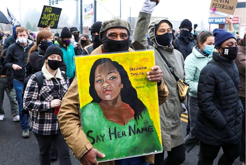 Kent Ford, co-founder of Portland, Ore.'s, Black Panther Party, carries a painting of Breonna Taylor during a march for Kevin E. Peterson Jr. who was killed by police in Vancouver, Wash., on Dec. 6.