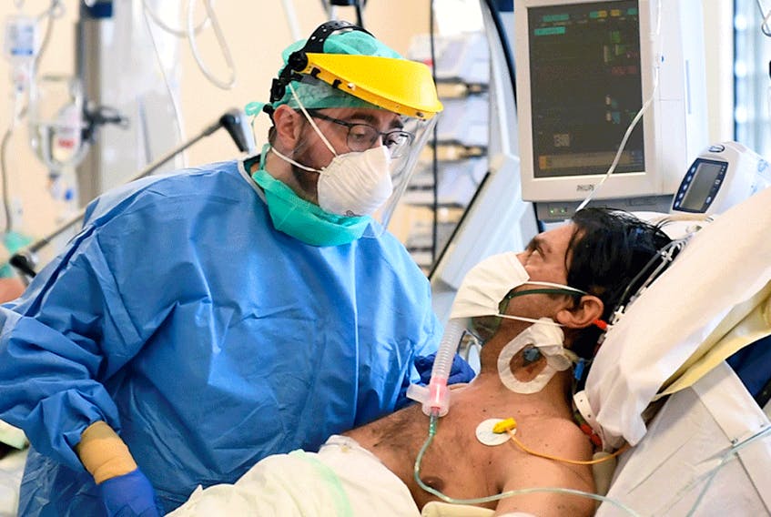 A medical staff member next to a patient suffering from COVID-19 in the intensive care unit at the Circolo hospital in Varese, Italy, April 9, 2020.